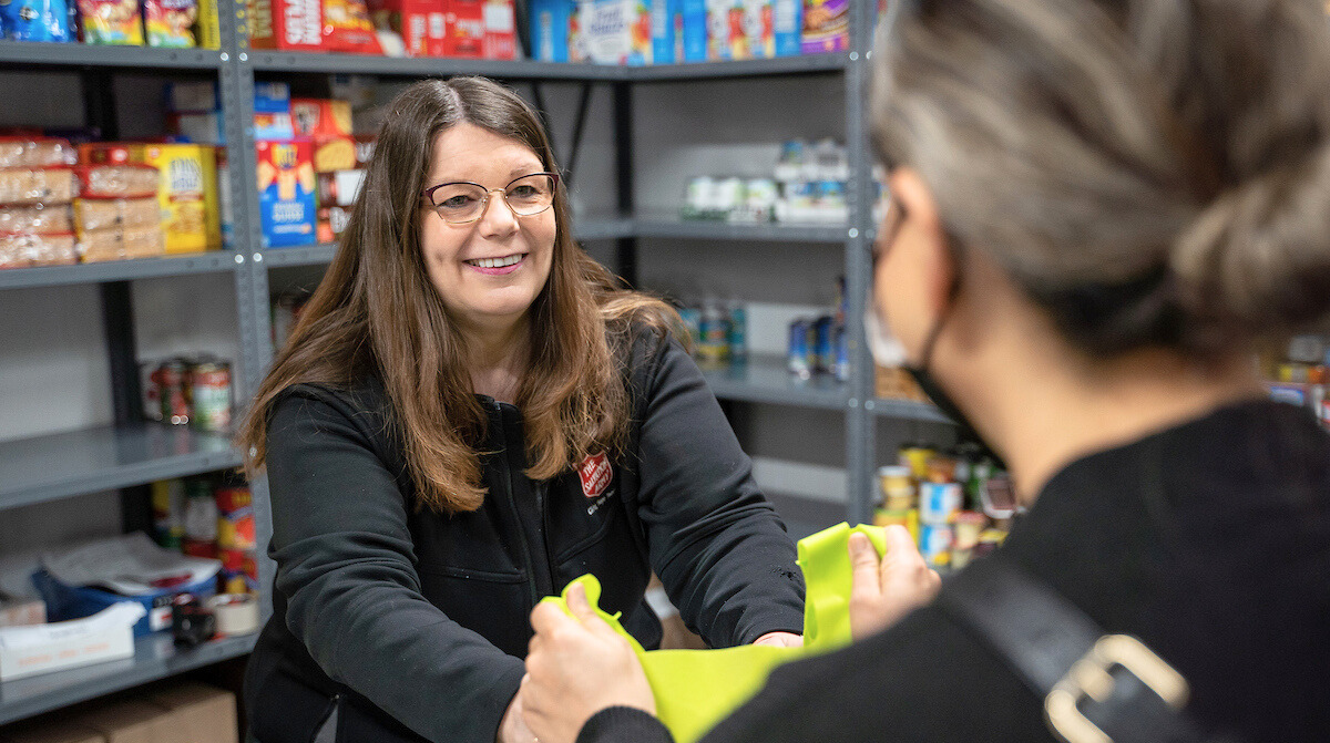 A staff member helping a client choose grocery items